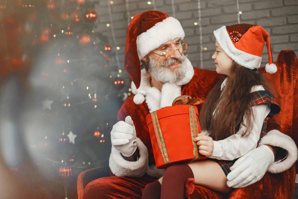 Child sitting on Santa's lap holding a present.