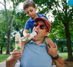 Child on parent's shoulders eating a pop